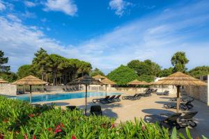 a swimming pool with umbrellas and lounge chairs at Camping Campo Di Liccia in Bonifacio