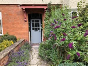 uma casa de tijolos com uma porta branca e flores roxas em Luxury 6 bedroom retreat in Stratford Upon Avon em Stratford-upon-Avon