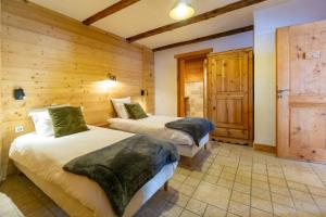 two beds in a room with wooden walls at Chalet Lyskamm in Montvalezan