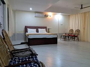 ein Schlafzimmer mit einem Bett und Stühlen in einem Zimmer in der Unterkunft Serene Blossom Valley in Tenkasi