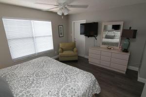 een slaapkamer met een bed, een televisie en een stoel bij Visit this top floor property located on the no-drive beach with 2 complex pools! in New Smyrna Beach