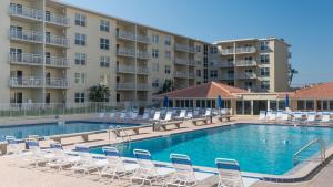 een zwembad met stoelen en een hotel bij Visit this top floor property located on the no-drive beach with 2 complex pools! in New Smyrna Beach