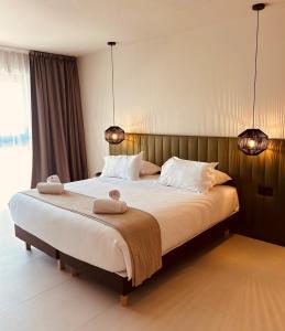 een slaapkamer met een groot bed en 2 handdoeken bij Hôtel Spa Restaurant La Madrague in Lucciana