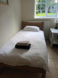a bedroom with a white bed with a towel on it at Private Bedrooms in Quaint Oxfordshire Village Cottage in Wantage
