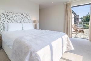 een witte slaapkamer met een groot bed en een balkon bij Luxurious house with hot tub near beach - Mallards in Thorpeness