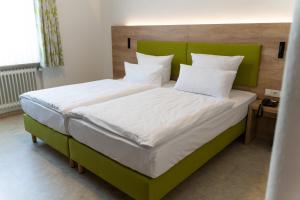 Schlafzimmer mit einem großen Bett mit einem grünen Kopfteil in der Unterkunft Hotel Bergschlößchen in Simmern