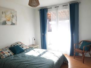 a bedroom with a bed with blue curtains and a window at GITE EN PROVENCE in Istres