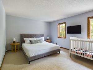 sypialnia z białym łóżkiem i łóżeczkiem dziecięcym w obiekcie Hazeltine Hideaway w mieście Chaska