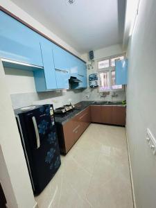 Kharar的住宿－Mona city homes，厨房配有蓝色橱柜和黑色冰箱。