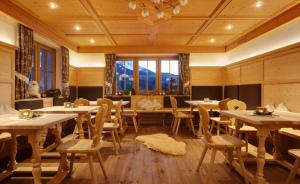 a restaurant with tables and chairs and a large window at Kräuterhotel Zischghof in Obereggen