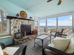 a living room with a stone fireplace with chairs and a table at Oakwood Beach - Lake Front - Geneva-On-The-Lake in Ashtabula