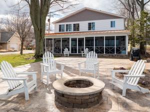 Oakwood Beach - Lake Front - Geneva-On-The-Lake في أشتابولا: مجموعة من الكراسي البيضاء وحفرة النار أمام المنزل