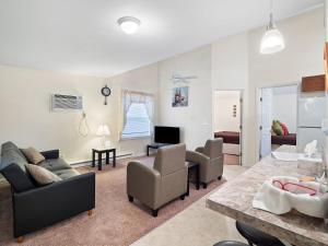 ein Wohnzimmer mit einem Sofa, Stühlen und einem TV in der Unterkunft The Riesling Cottage - GOTL Strip - Cozy & Quaint in Geneva