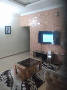 a living room with a tv on a brick wall at 2 bedroom service apartment with full services in Idimu