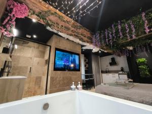 a bath tub in a room with a tv and flowers at L'éxperience LOVE ROOM in LʼÉtrat