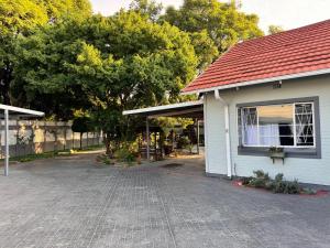 a white house with a red roof and a driveway at Blue Lantern Bed and Breakfast in Kempton Park