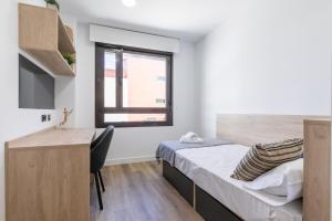 um quarto com uma cama, uma secretária e uma janela em micampus Wynwood - Tovar em Madrid
