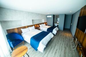 a hotel room with two beds and a table and chairs at Café Hotel Medellín in Medellín