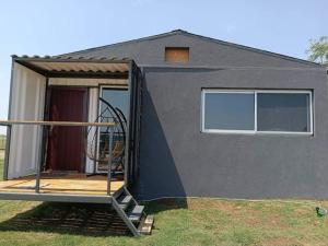 ein kleines Haus mit einer Veranda und einer Terrasse in der Unterkunft Alojamiento con pileta en Cañuelas in Cañuelas