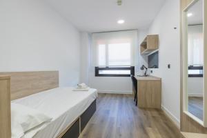 1 dormitorio con cama, escritorio y ventana en micampus Wynwood - Tovar en Madrid