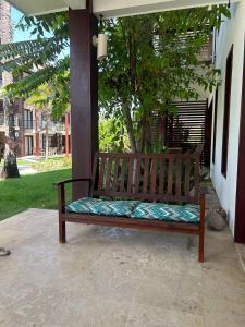 drewniana ławka siedząca na ganku z drzewem w obiekcie Taiba Beach Resort w mieście Taíba