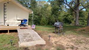 a tent with a grill and a table and a grill at Khushatta Hills Ranch Glamping - Mom Mollie in Coldspring