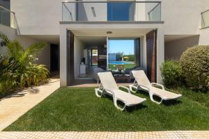two white lounge chairs on the grass in front of a house at Villa Blue Sagres D in Sagres