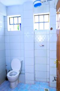 een witte badkamer met een toilet en een raam bij CALMCORNER HAVEN HOMES, PATRIDE ENTERPRISES in Kisii