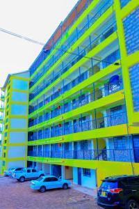 un bâtiment jaune avec des voitures garées dans un parking dans l'établissement CALMCORNER HAVEN HOMES, PATRIDE ENTERPRISES, à Kisii