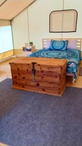 a bedroom with a bed with a wooden dresser at Khushatta Hills Ranch Glamping - Mom Mollie in Coldspring
