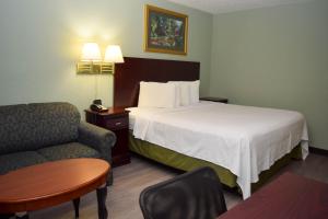 um quarto de hotel com uma cama e uma cadeira em Corning Inn em Painted Post