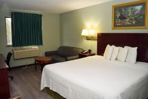 a hotel room with a large bed and a chair at Corning Inn in Painted Post