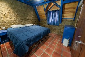 a bedroom with a blue bed in a brick wall at ÑAÑO V in San Antonio de las Alzanas
