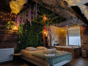 a bedroom with a bed and a bath tub and flowers at L'éxperience LOVE ROOM in LʼÉtrat