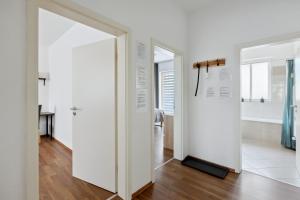 a hallway with white walls and a door with a mirror at Ankommen und entspannen! in Merseburg