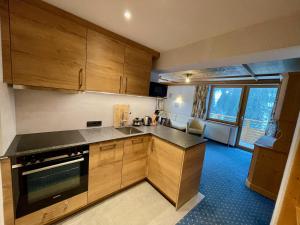 a kitchen with wooden cabinets and a large window at Alkira in Sankt Anton am Arlberg