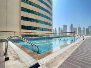 a swimming pool in front of a tall building at Marasi Moods 2BD on Burj Khalifa and Canal views in Dubai