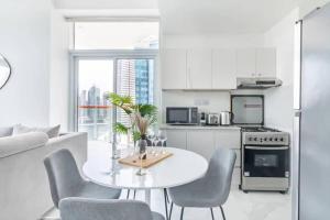 a white kitchen with a white table and chairs at Marasi Moods 2BD on Burj Khalifa and Canal views in Dubai