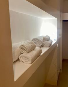 - une étagère blanche avec des serviettes dans la salle de bains dans l'établissement House Blue Roses Apartment Step Up in Puglia for your Niksen, à Bari