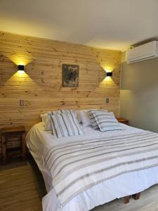 a bedroom with a large white bed with wooden walls at Hotel Bacaris in Puerto Tranquilo