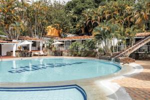 a pool at a resort with palm trees in the background at Hotel Quimbaya in San Jerónimo