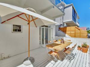 una mesa de madera y sillas con una sombrilla en la terraza en Tranquil Family Home in Green Point, en Ciudad del Cabo