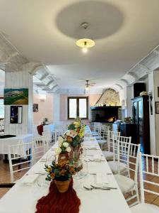 una mesa larga con sillas blancas y flores. en Agriturismo Oasi Biologica, en Montedinove