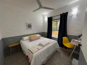 a bedroom with a bed with two chairs and a window at Santorini - Kallisti 25, Ballito Family only in Ballito