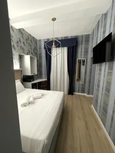 1 dormitorio con 1 cama blanca y TV en ROME'S GLORIA HOTEL en Roma