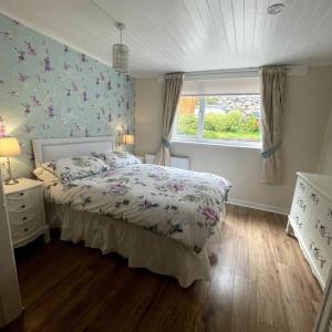 a bedroom with a bed and a window at Country Cottage with Hot-Tub and Cosy Log Burner in Tregarth