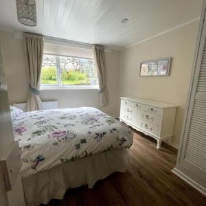 Country Cottage with Hot-Tub and Cosy Log Burner في Tregarth: غرفة نوم بسرير وخزانة ونافذة