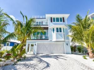 uma casa branca na praia com palmeiras em Ocean Breeze (AMIL) em Bradenton Beach
