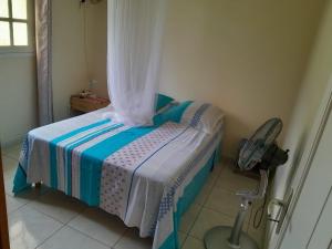 a small bedroom with a bed and a chair at Les Dalhias in Les Anses-dʼArlets