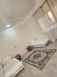 a living room with two beds and a rug at Sunset view hill jabal shams in Misfāh